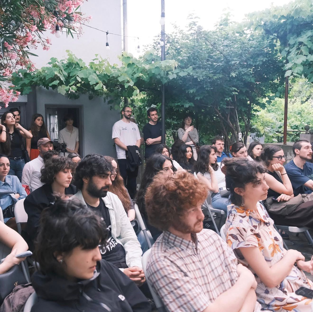 Listeners arranged across the courtyard space